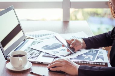 Bir smartphone ve bir dizüstü bilgisayar ile bir belgeyle bir kahve dükkanında çalışan kadar yakın işadamları.