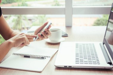 Bir smartphone ve bir dizüstü bilgisayar ile bir belgeyle bir kahve dükkanında çalışan kadar yakın işadamları.