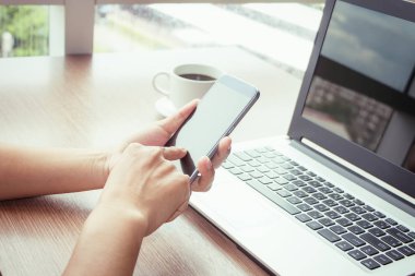 Bir smartphone ve bir dizüstü bilgisayar ile bir belgeyle bir kahve dükkanında çalışan kadar yakın işadamları.