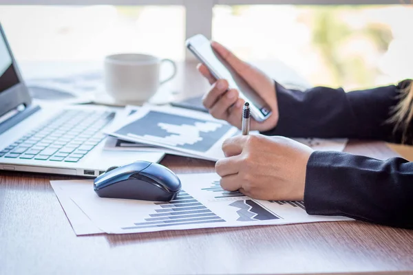 Bir smartphone ve bir dizüstü bilgisayar ile bir belgeyle bir kahve dükkanında çalışan kadar yakın işadamları.