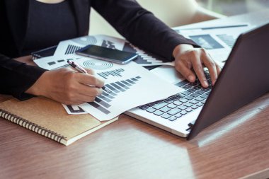 Bir smartphone ve bir dizüstü bilgisayar ile bir belgeyle bir kahve dükkanında çalışan kadar yakın işadamları.