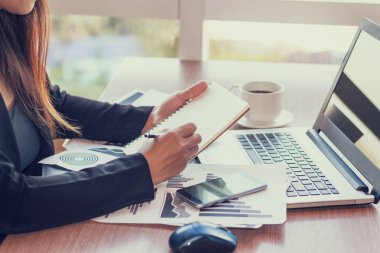 Bir smartphone ve bir dizüstü bilgisayar ile bir belgeyle bir kahve dükkanında çalışan kadar yakın işadamları.