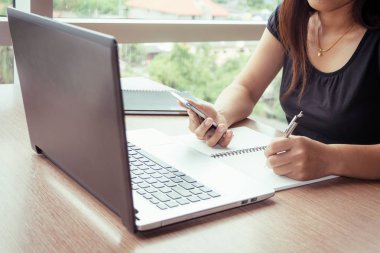 Bir smartphone ve bir dizüstü bilgisayar ile bir belgeyle bir kahve dükkanında çalışan kadar yakın işadamları.