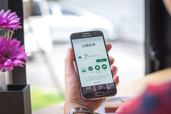 Chiang Mai, Thailand - September 12, 2017: Samsung Galaxy S6 smartphone launches uber driver application on the desk screen at the coffee shop.