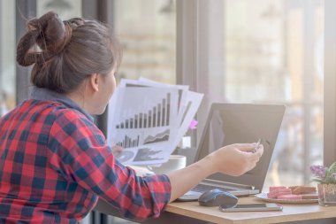 Bir smartphone ve bir dizüstü bilgisayar ile bir belgeyle bir kahve dükkanında çalışan kadar yakın işadamları.