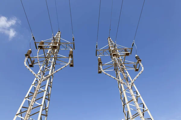 Pilones de electricidad contra el cielo azul — Foto de Stock