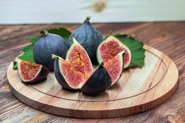 A few vivid cuted figs on a plate on an old wooden background — Stock Photo, Image