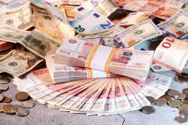 Büyük banknotlar, Rus rublesi ve gri bir yüzey üzerinde duran farklı madeni paraların hayranı.