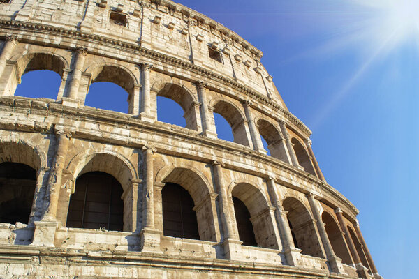 Colosseum at blue sky with sunlight. Rome ancient arena for gladiator fights in Italy