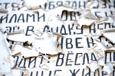 Kırık beyaz yüzeydeki Kiril alfabesi siyah harfler. Arkaplan dokusu, üst görünüm, bulanık. Okunamayan metin