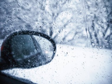 Karlı havada su damlaları olan arabanın dikiz aynası görüntüsü