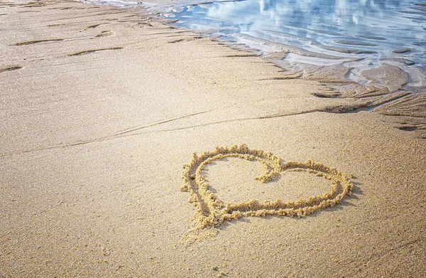 A heart in the sand in the sea water on the beach