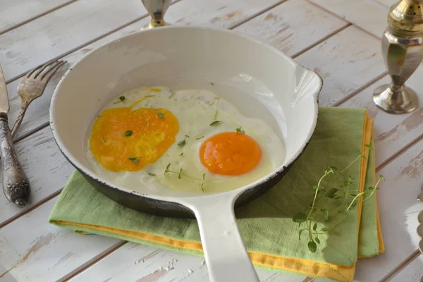 Scrambled eggs in a white frying pan on a wooden shabby background — Stock Photo, Image