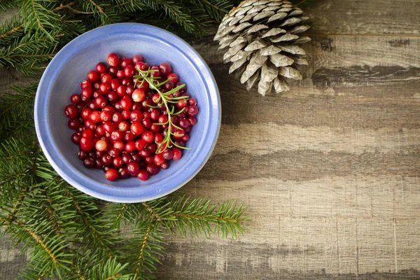 Flat lay image of fresh cranberry or cowberry on wooden rustic background with cone and pine branch, copy space — Stock Photo, Image