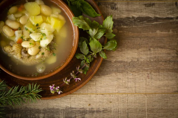 Rustic winter soup of russian cuisine, bowl of chicken soup with beans. Top view, copy space