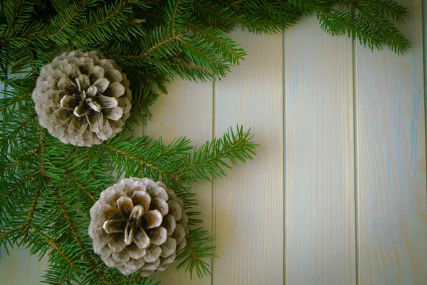 Decorazione natalizia con luci di Natale e coni su sfondo blu in legno — Foto Stock