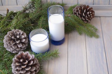 Noel zamanı, iki mavi bardak sütlü çam dalı ve mavi ahşap masa üzerinde koniler, kopyalama alanı