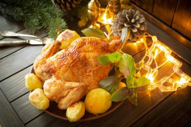 Patatesli altın tavuk ve karanlık köy masasında Noel aydınlatması.