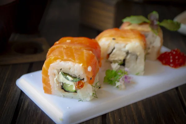 Sushi de salmão em um prato branco. Sushi roll Alasca ou Filadélfia com peixe vermelho, salmão, caviar vermelho. Rolo com salmão fresco, abacate macio e queijo creme de perto — Fotografia de Stock