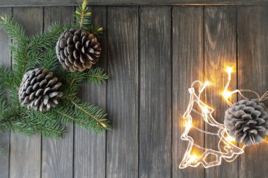 Noel arkaplanı köknar dalları ve çam kozalakları, Noel ağacı şeklinde aydınlatma çelenkleri