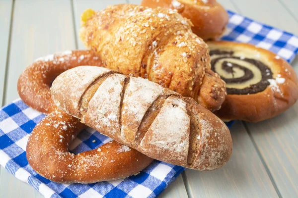 Assortment of baked breads and golden buns, russian cuisine, vintage blue napkin — Stock Photo, Image