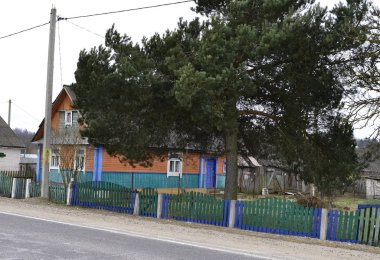 Sabah Belarus kırsalındaki karlı tepeler, kırmızı ahşap kırsal ev, kış manzarası