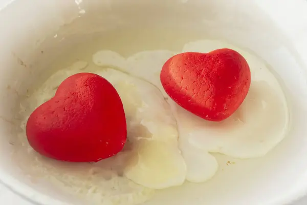 Uova fritte con cuori rossi su sfondo bianco. Concetto d'amore di San Valentino. Da vicino. — Foto Stock