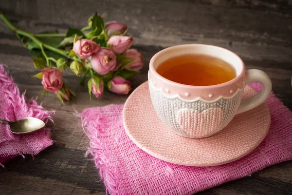 Close-up de uma xícara de chá com rosas e doces de chocolate na mesa de madeira — Fotografia de Stock