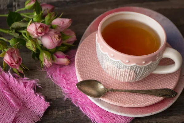 Rosa de malha xícara de chá com coração no fundo escuro decorado com rosas rosa — Fotografia de Stock