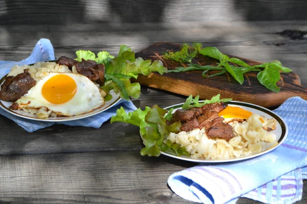 Macarrão com legumes carne grelhada e gema de ovo assada na mesa de madeira escura — Fotografia de Stock