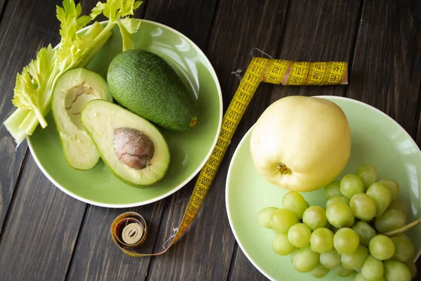 Alimentação saudável, dieta, emagrecimento e conceito de perda de peso. Vista superior, maçã verde, abacate, aipo e uvas com fita métrica, legumes verdes — Fotografia de Stock