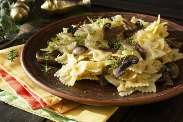 pasta with cheese sauce, mushrooms and thyme on dark rustic table