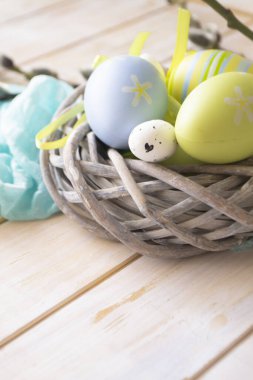 Beyaz eski ahşap arka planda bir yuvada renkli Paskalya yumurtaları kopyalama alanı ve dikey görüntü alanı