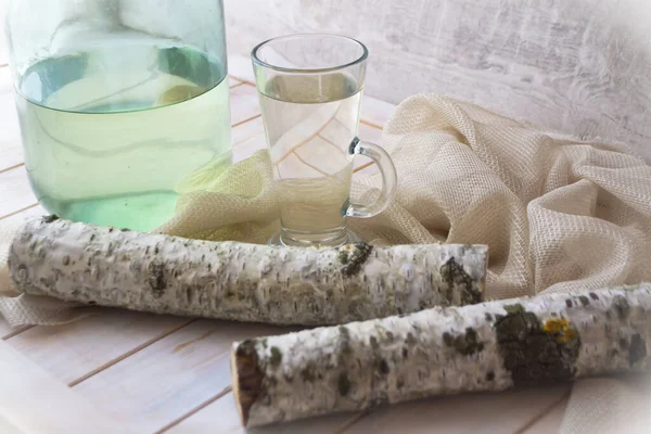 Bebida de vitamina útil de primavera. Suco de vidoeiro frio fresco em um jarro e ramos de vidro e vidoeiro em um contexto de madeira. Conceito de alimentos saudáveis e vitamínicos — Fotografia de Stock