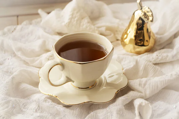 Tasse de thé blanc en porcelaine avec décoration dorée sur une serviette vintage blanche — Photo