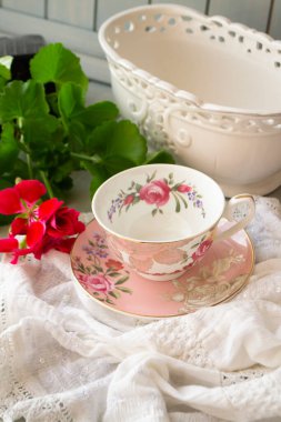 Dantel masa örtüsü üzerinde antik porselen çay fincanı, dikey görüntü.