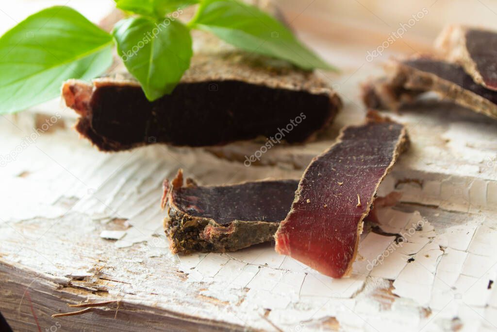 Thin slices of deer sausages or dry roe meat served on a white board