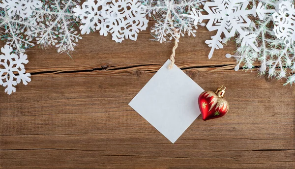圣诞贺卡上有雪花和圣诞玩具 空纸上装的是假的 木制背景的新年饰物 圣诞节庆祝的概念 文本的位置 平面布局 顶部视图 复制空间 — 图库照片