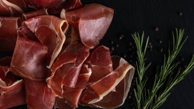 Ahşap arka planda biberiyeli Prosciutto Crudo veya Jamon. İtalyan Antipasto. Geleneksel İspanyol Jamon Serrano jambonu, Prosciutto Crudo, Parma jambonu