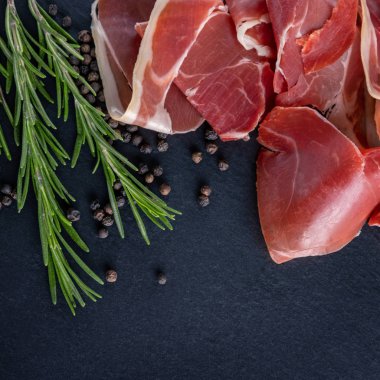Ahşap arka planda biberiyeli Prosciutto Crudo veya Jamon. İtalyan Antipasto. Geleneksel İspanyol Jamon Serrano jambonu, Prosciutto Crudo, Parma jambonu