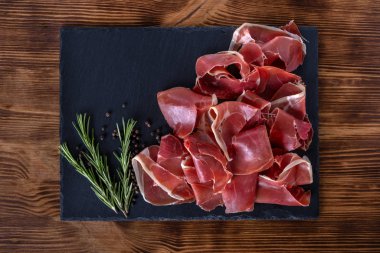 Ahşap arka planda biberiyeli Prosciutto Crudo veya Jamon. İtalyan Antipasto. Geleneksel İspanyol Jamon Serrano jambonu, Prosciutto Crudo, Parma jambonu
