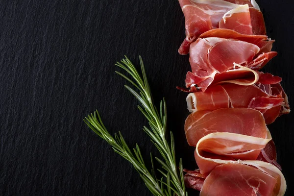 Prosciutto Crudo Jamón Con Romero Sobre Pizarra Negra Sobre Fondo —  Fotos de Stock