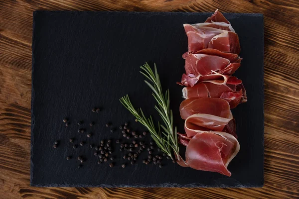 Prosciutto Crudo Jamon Com Alecrim Placa Preta Sobre Fundo Madeira — Fotografia de Stock