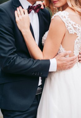 Yay ile siyah elbiseli damat gelin beyaz elbisenin içinde tutar.