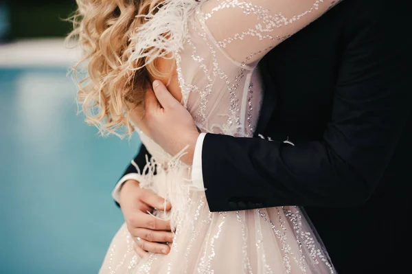 幸せな花嫁と新郎は互いに抱擁し 花嫁は美しい輝くウェディングドレスを身に着けており 新郎は黒のスーツにあり クローズアップ — ストック写真
