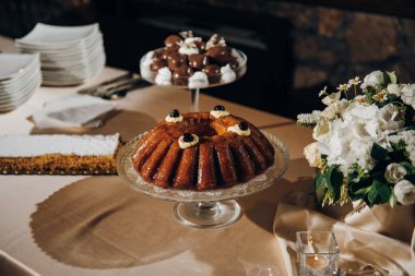 Geleneksel İtalyan Rom Baba masada, başka tatlılar ve masada taze çiçekler var.