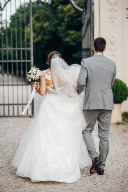 Gelinlik giymiş gelin ve damat parkta yürüyor.