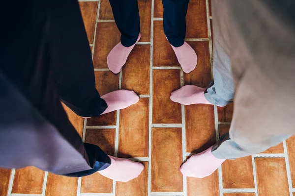 Groom and his friends in pink socks stand nearby, top view on legs