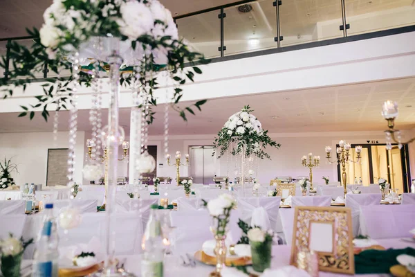 白い花と緑の構成で飾られた結婚式の宴会テーブルは カトラリーやキャンドルがあります — ストック写真