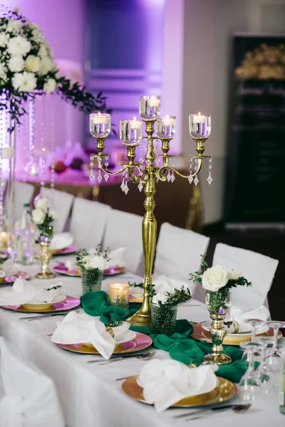 結婚式 白い花と緑の花の配置は キャンドルで飾られた 祭りのテーブルの上にあり カトラリーや食器で提供され 白いテーブルクロスと緑のリボンで覆われています — ストック写真